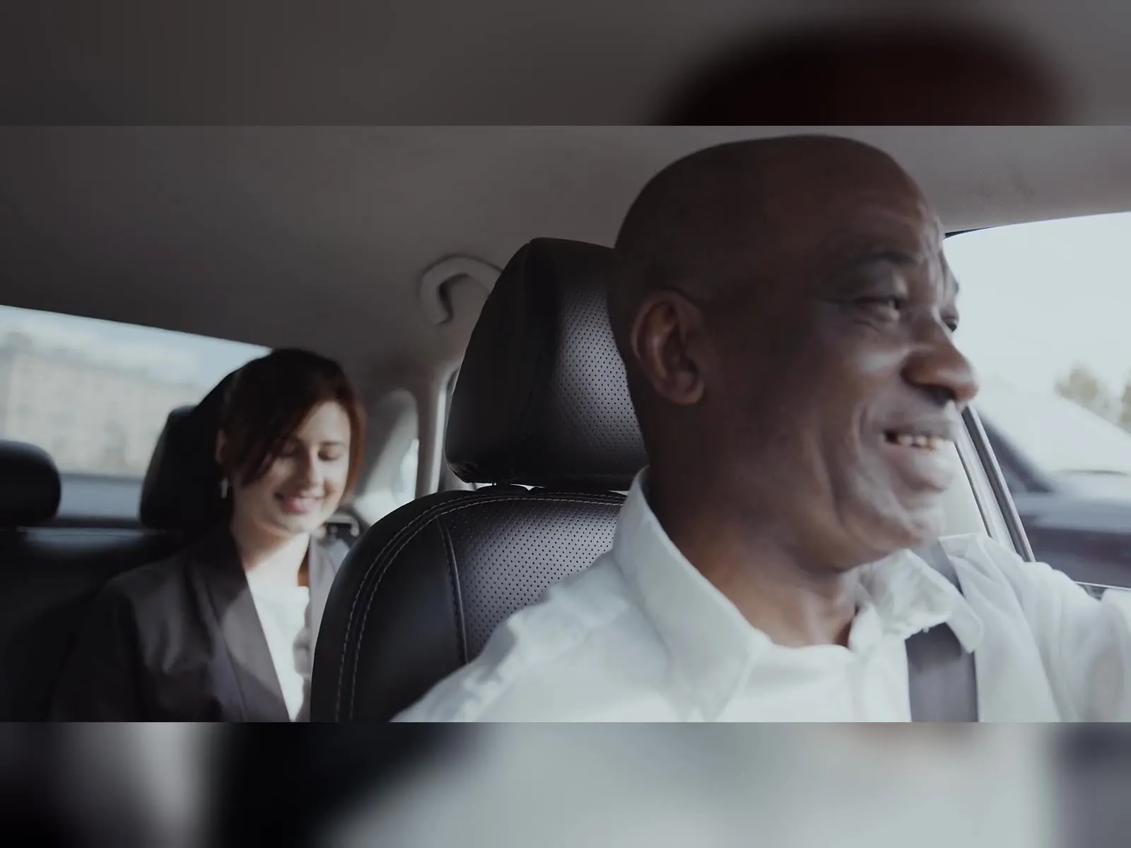 Smiling rideshare driver chatting with a passenger in the back seat