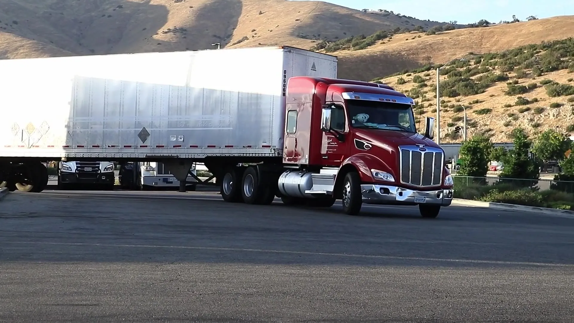 Red semi truck pulling a trailer along the road